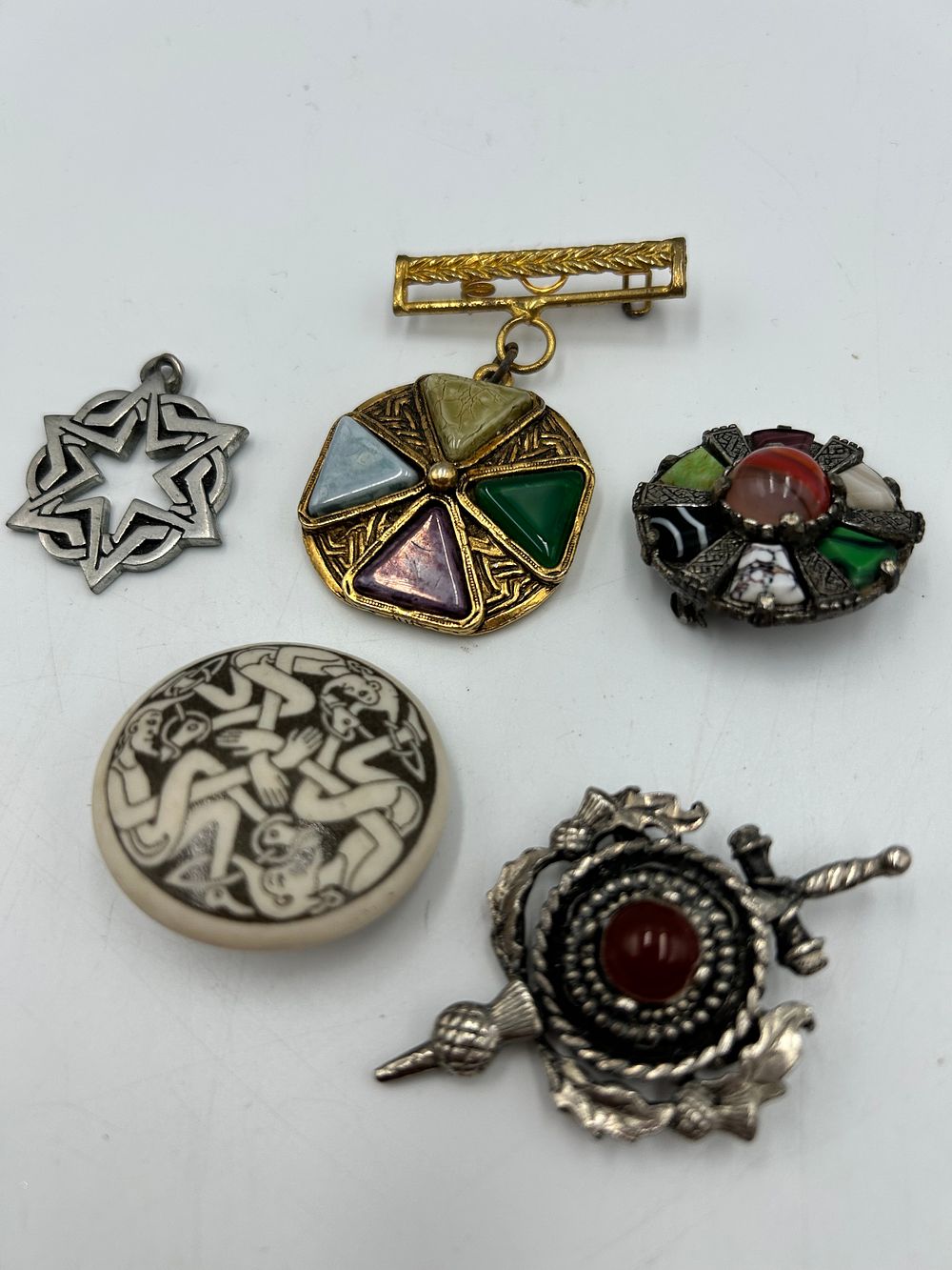 Lot 634: A Collection of Scottish and Celtic Style White Metal and Gilt-Metal Effect Brooches and Pendants
