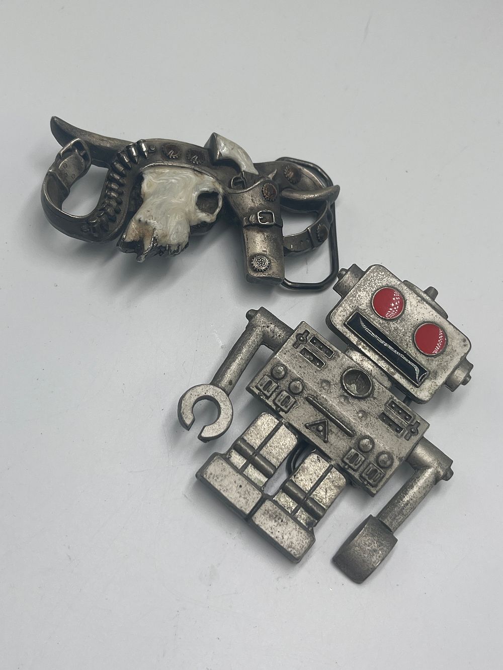 Lot 729: Two Cast White Metal Enamelled Belt Buckles by Mobtown, 2003 and 2005