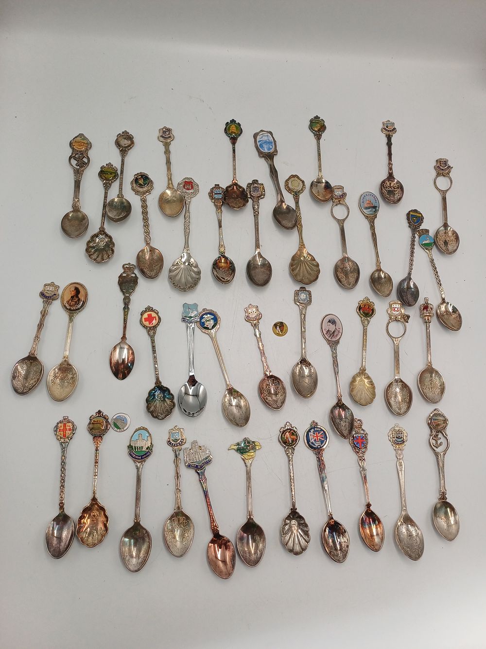 Lot 935: A Collection of White Metal and Enamelled Souvenir Spoons