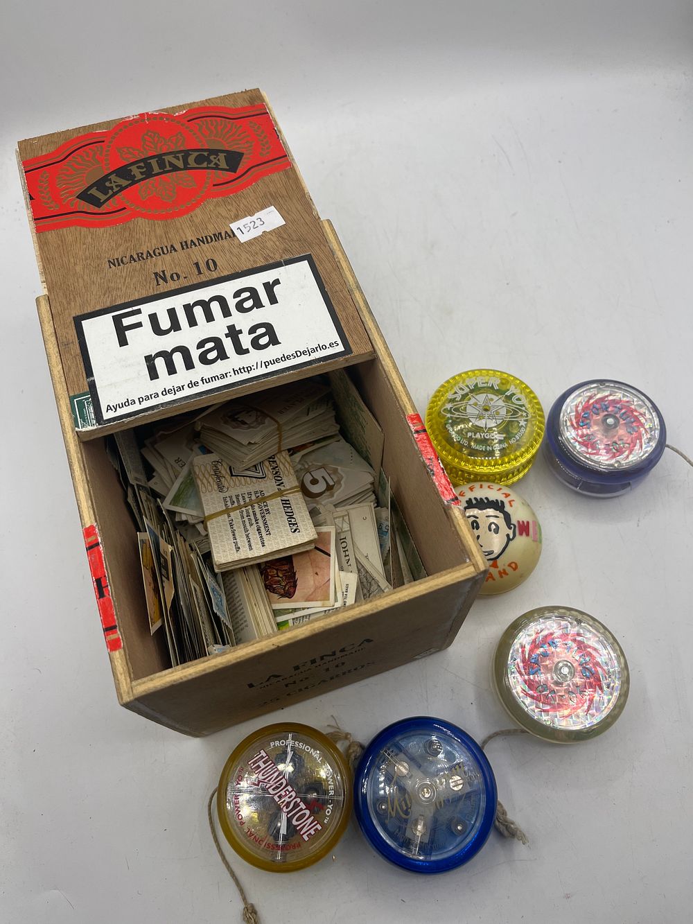 Lot 1082: A Collection of Plastic Yoyos and Cigarette Cards in a Wooden La Finca Cigar Box