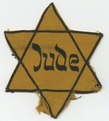 טלאי צהוב של יהודי מגרמניה, ראשית שנות ה־40. טלאי צהוב מבד בצורת מגן דוד עם הכיתוב JUDE במרכזו. 