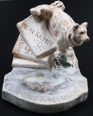 מאפרה אנטי - נאצית - 'הכלב החכם'. סביב 1940. מאפרת אבן אנטי-נאצית. כלב עושה צרכיו על ספרי 'מיין 