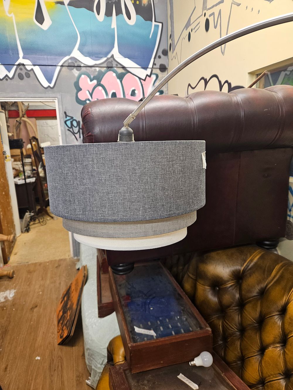 Lot 385 – A contemporary brushed metal arc floor lamp with three-tiered textile shade