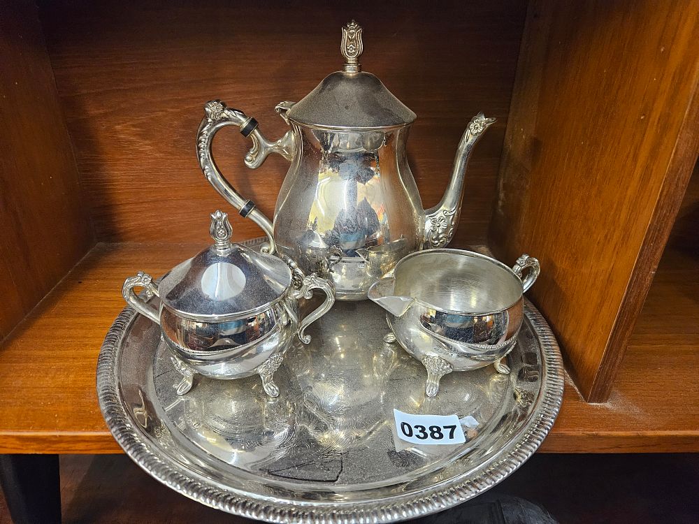 Lot 387 – A four-piece silver-plated tea service on a circular tray