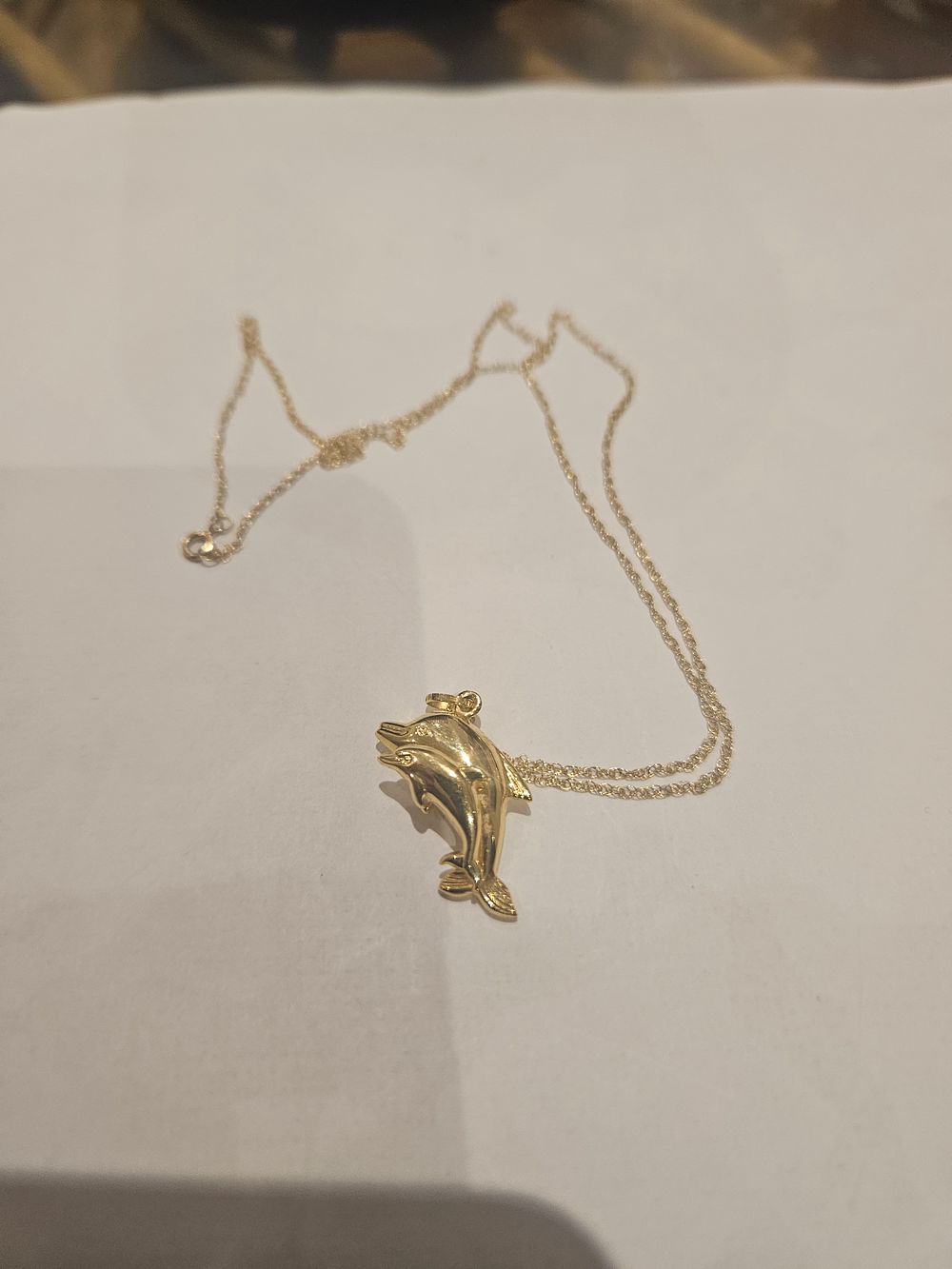 Lot 447 – A 9ct gold leaping dolphin pendant on a fine curb-link chain 1.8grams