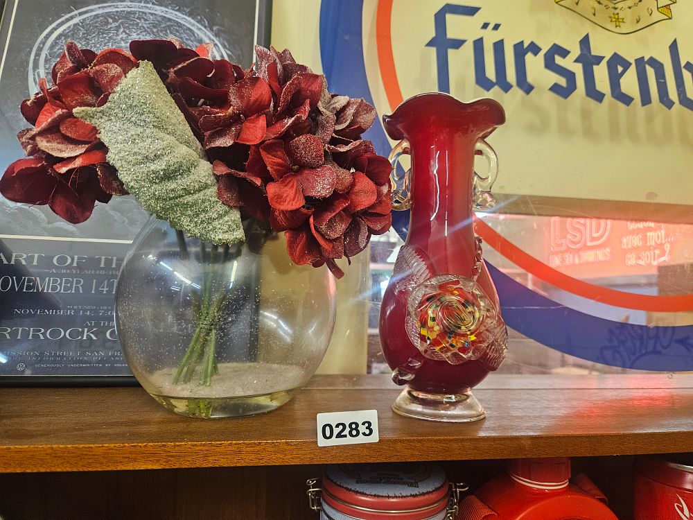 Lot 283 – A Two-Piece Lot Comprising a Ruby Red Glass Vase in the Murano Style and a Spherical Glass Vase with Artificial Floral Arrangement