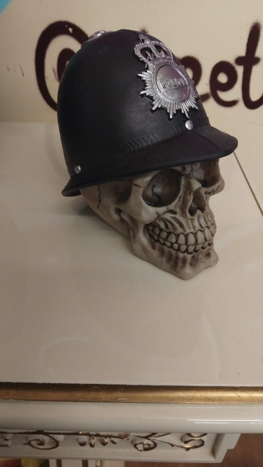 Lot 277 – A Novelty Resin Skull Sculpture Wearing a British Police Custodian Helmet