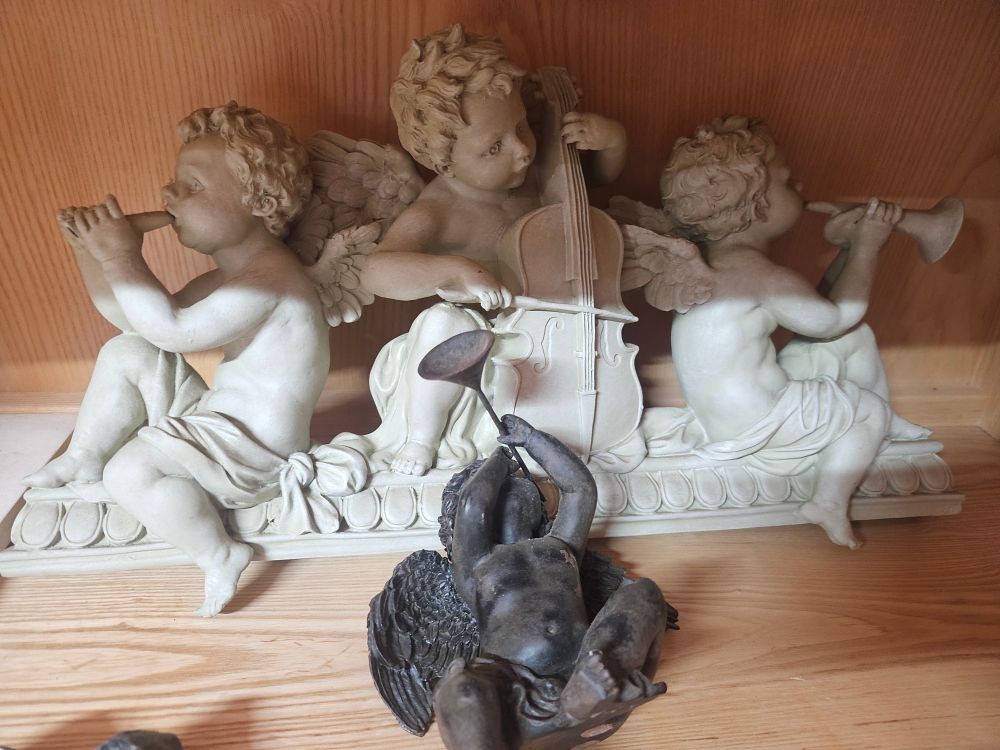 Lot 261 – Two decorative figurines comprising a musical cherub wall pediment in the style of Design Toscano and a separate patinated cherub 1 af