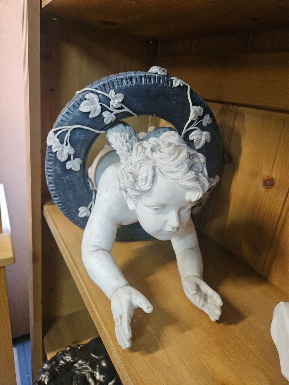 Lot 266 – A Contemporary Composite Decorative Wall Sculpture of a Cherub with a Vehicle Tire