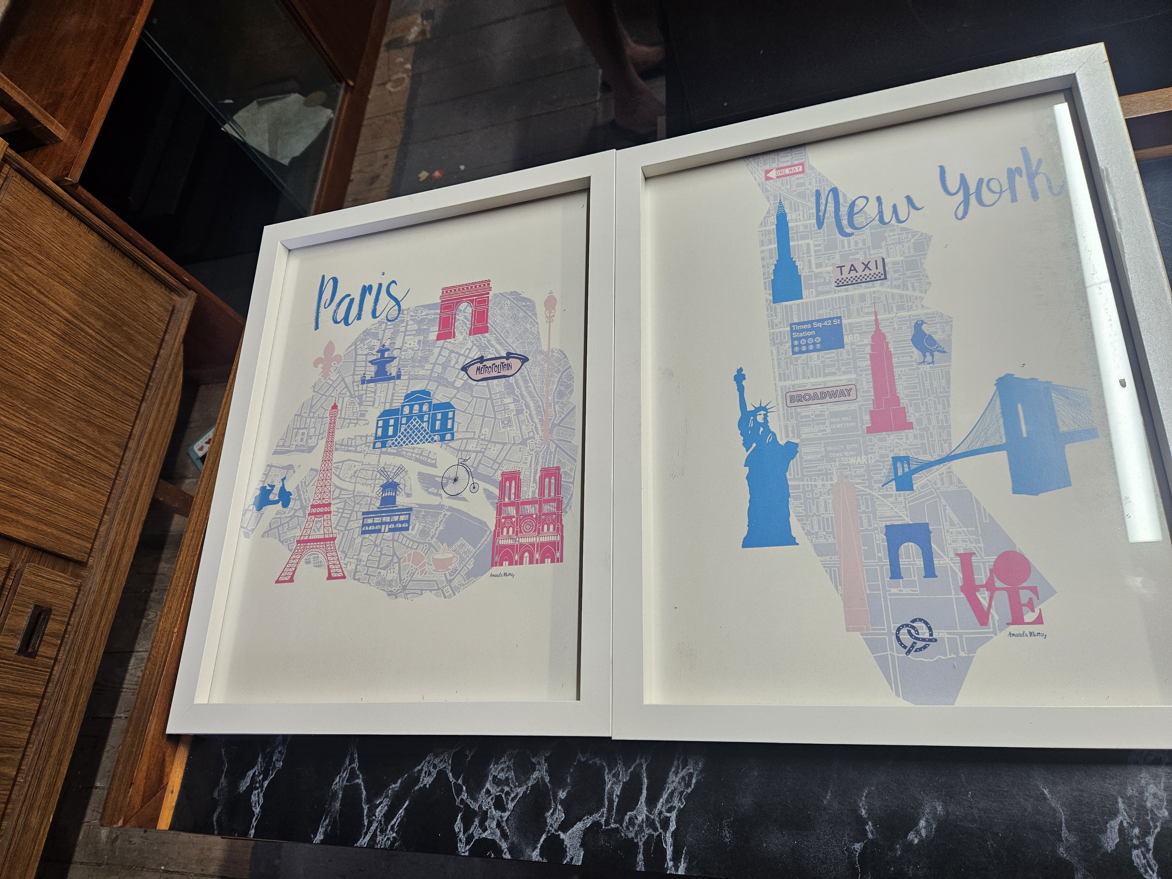 A Pair of Amanda Murray Framed Whimsical Map Prints, Paris and New York