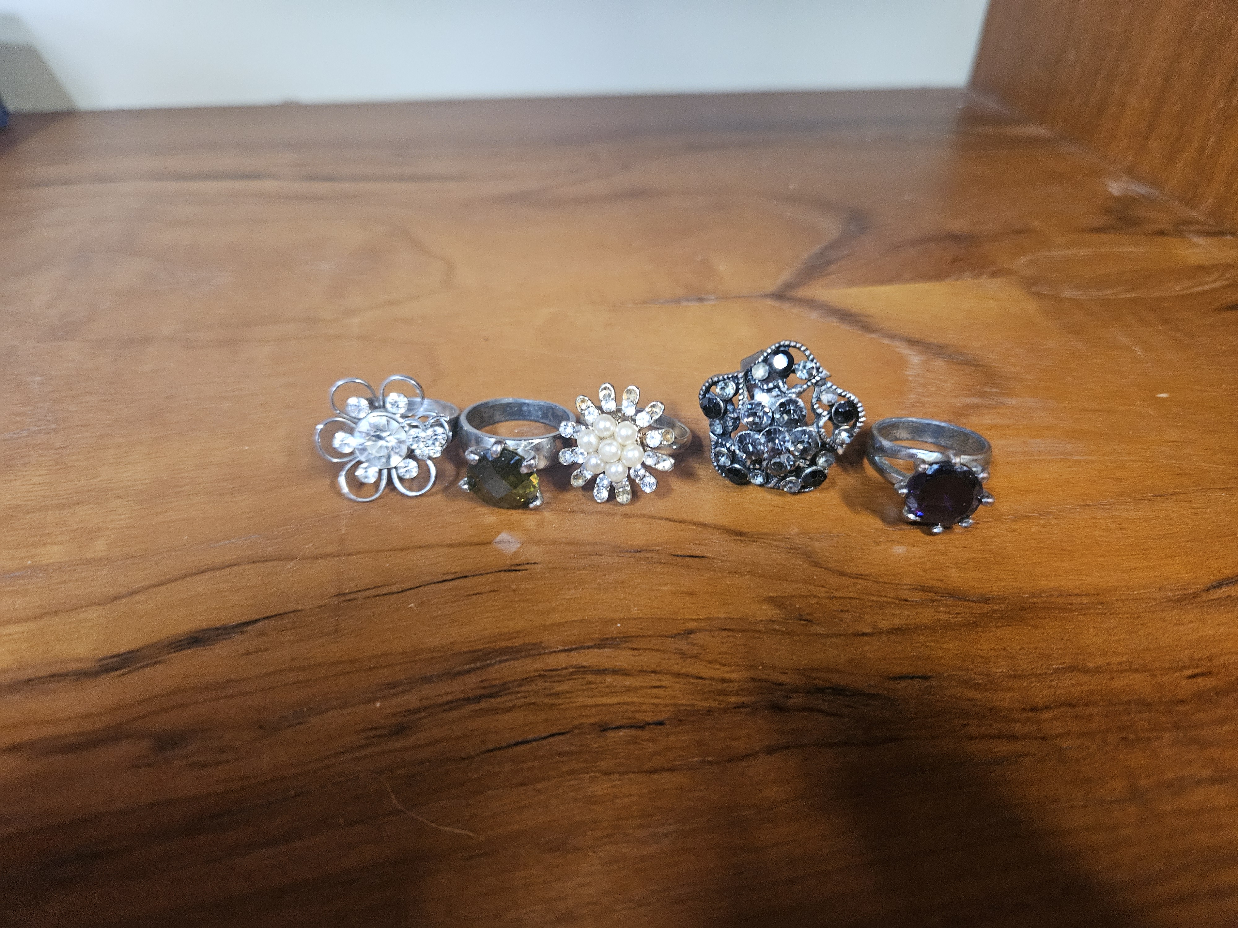 A collection of five silver-tone costume jewellery rings including floral and solitaire designs