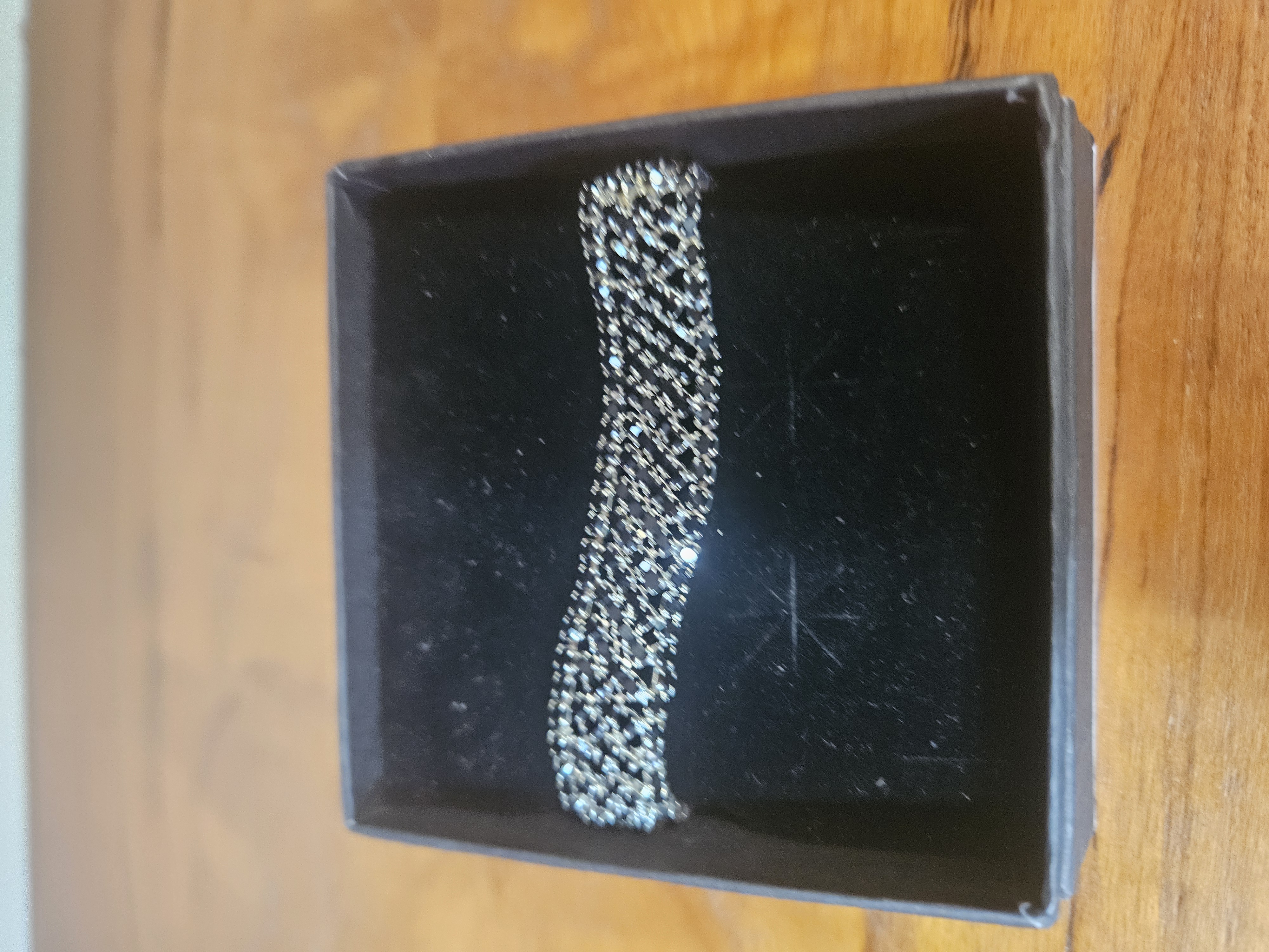 A black wide woven mesh link bracelet set with stones