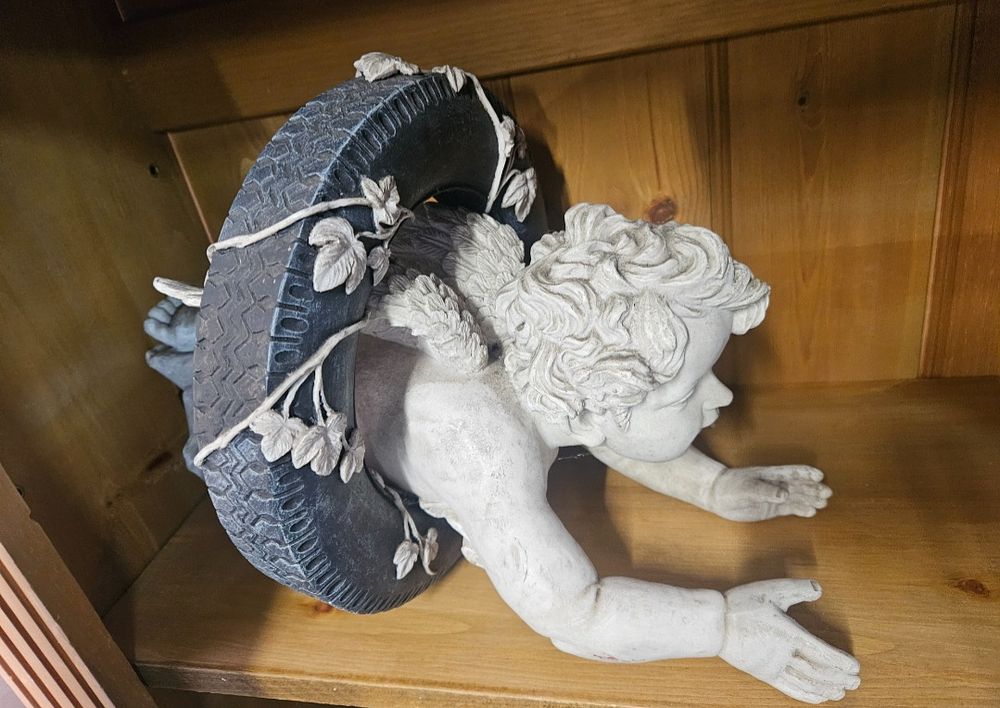 Lot 179 – A Contemporary Cast Composite Sculpture of a Winged Cherub Crawling Through a Tyre