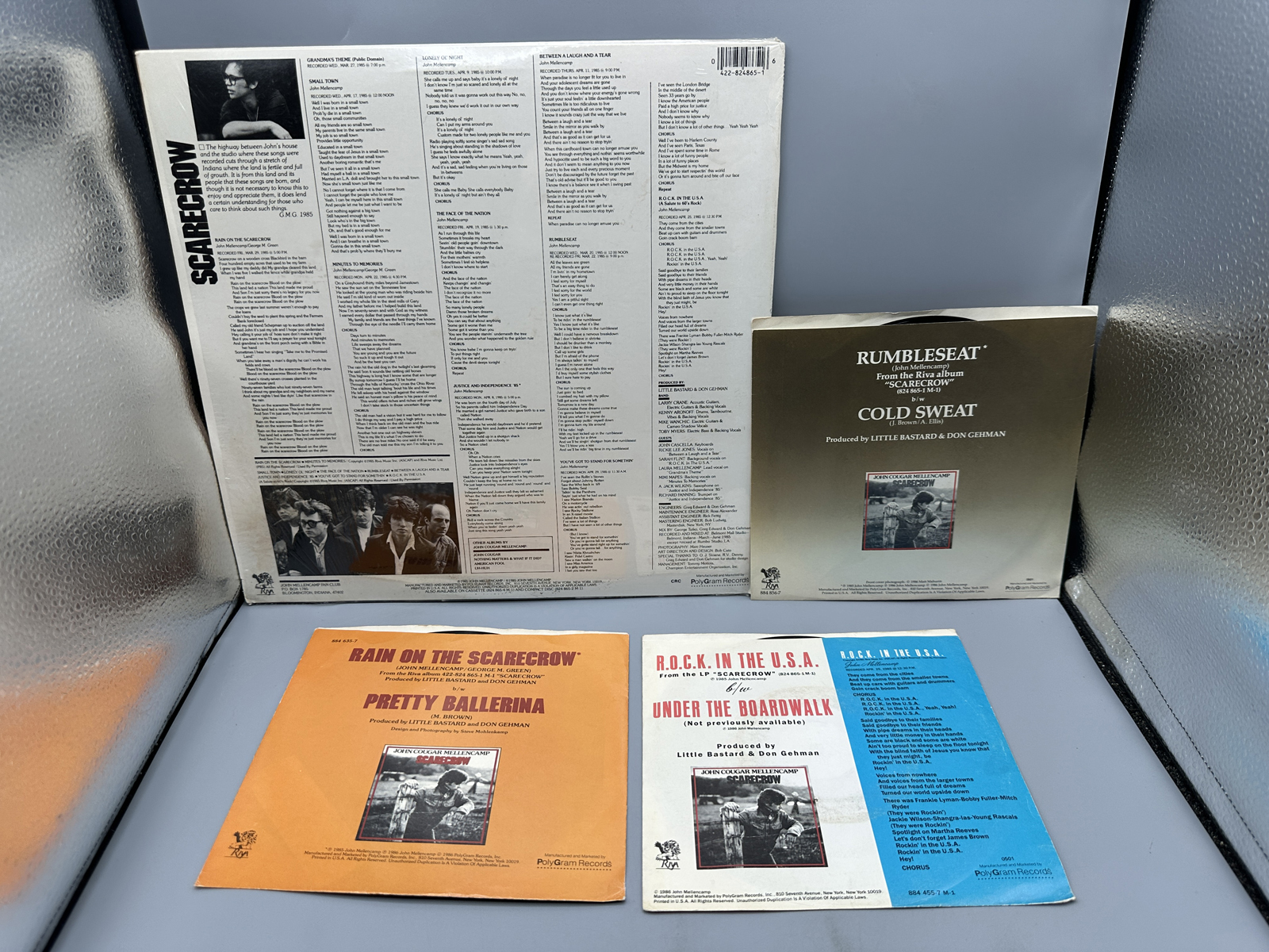 John Cougar Mellencamp: Scarecrow (1985), Club Edition; AND Three (3) 7-inch 45 rpm records with picture sleeves: Rumbleseat; Rain On the Sc