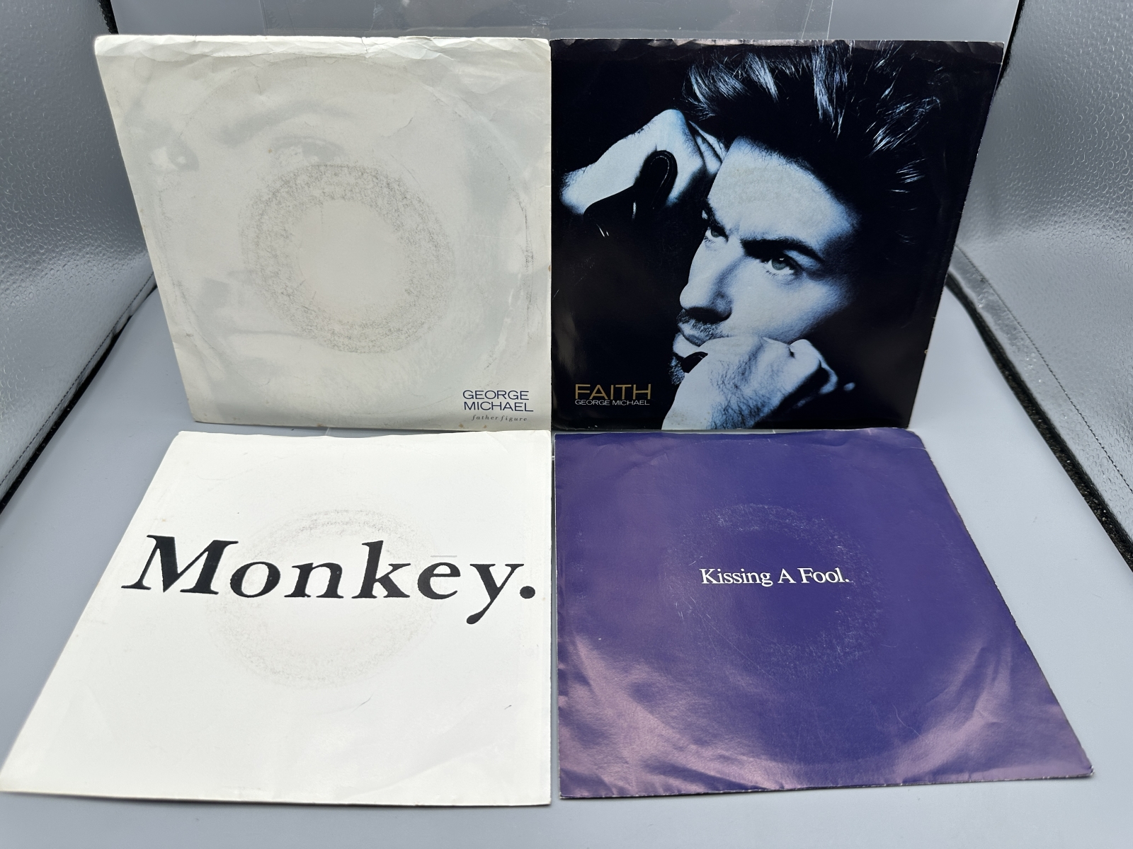 George Michael: Six (6) 7-inch 45 rpm records with picture sleeves: Faith (1987); Father Figure (1987); Monkey (1988); Kissing A Fool (1988)