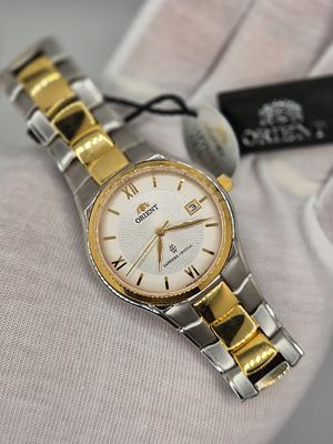 שעון של חברת Orient עדיין עם תגית מחיר עליו במצב מעולה עם לוח בצבע לבן פנינה ותצוגת תאריך 