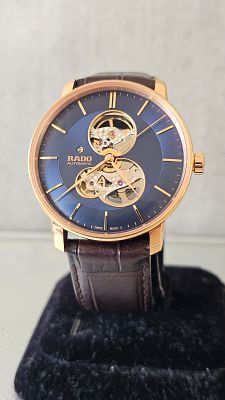 שעון Rado יפייפה עם גוף בצבע זהב, לוח בצבע כחול, מנגנון אוטומטי, דגם Open Heart לצפייה במנגנון 
