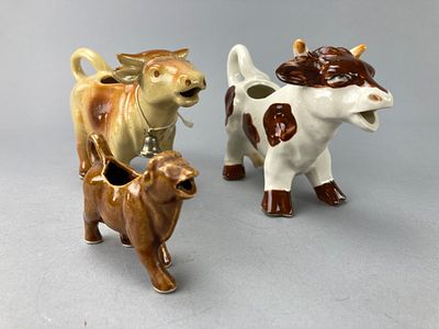 Three Ceramic Cow-Shaped Creamers with Bell. Group of three ceramic cow-shaped creamers. Each 