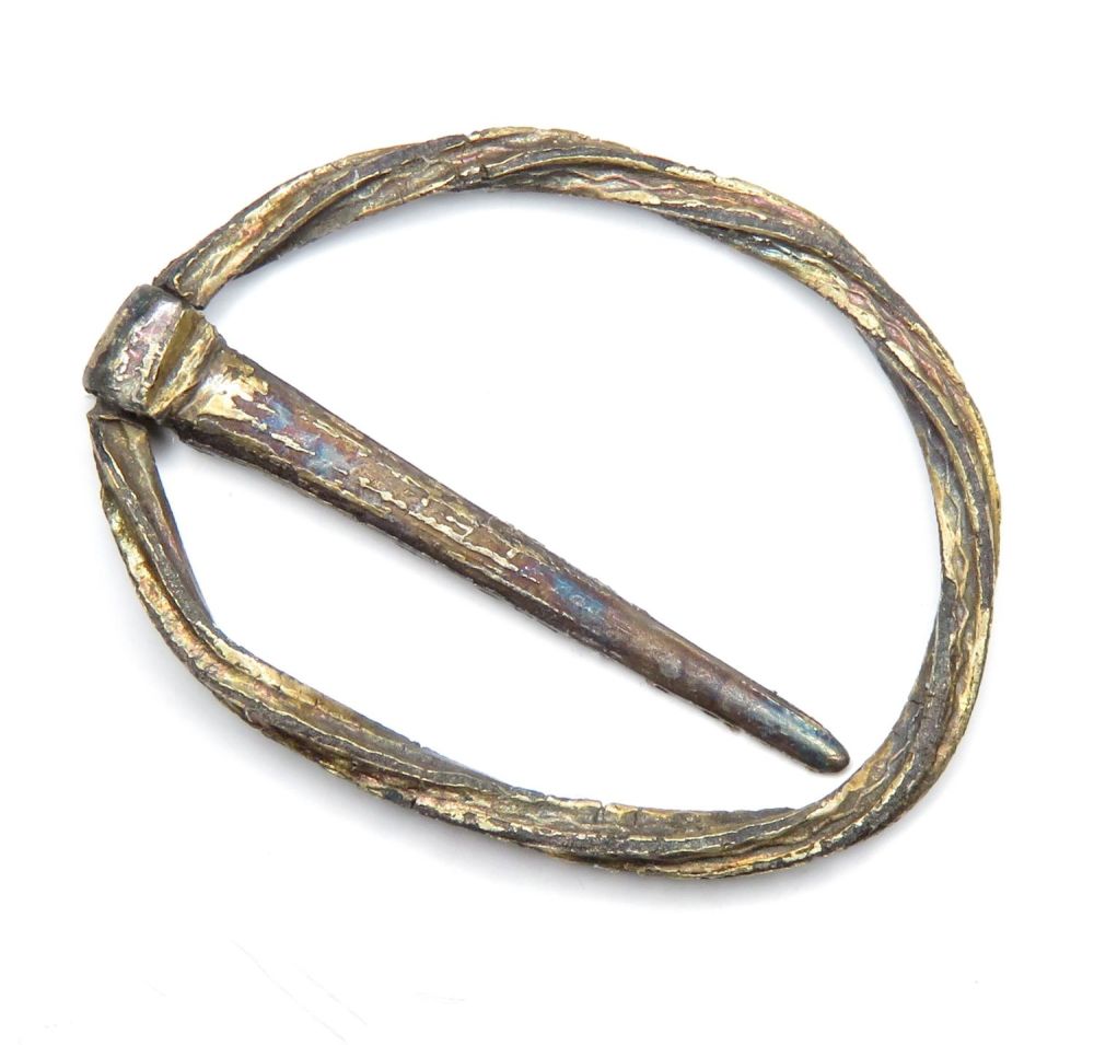 Lot 1089: Medieval silver-gilt annular brooch. A silver ring brooch...