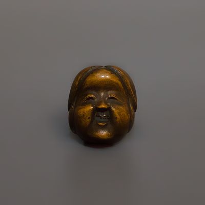 Нэцкэ &laquo;Маска Окамэ&raquo;. Япония, 19 век. 
Дерево, резьба. 
Высота: 4 см. 
Подпись мастера. 