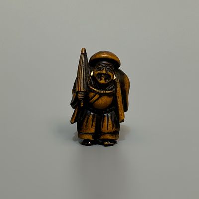 Нэцкэ &laquo;Дайкоку с зонтом&raquo;. Япония, 19 век. 
Дерево, кость, резьба. 
Высота: 3,5 см. 
