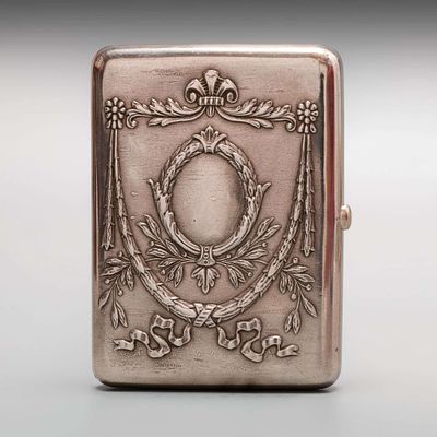 Портсигар с медальоном в центре в обрамлении гирлянды из лент и растений. Серебро, остатки 