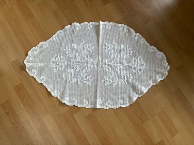 Centerpiece. Decorative white lace cloth with handmade floral design. Signs of use.