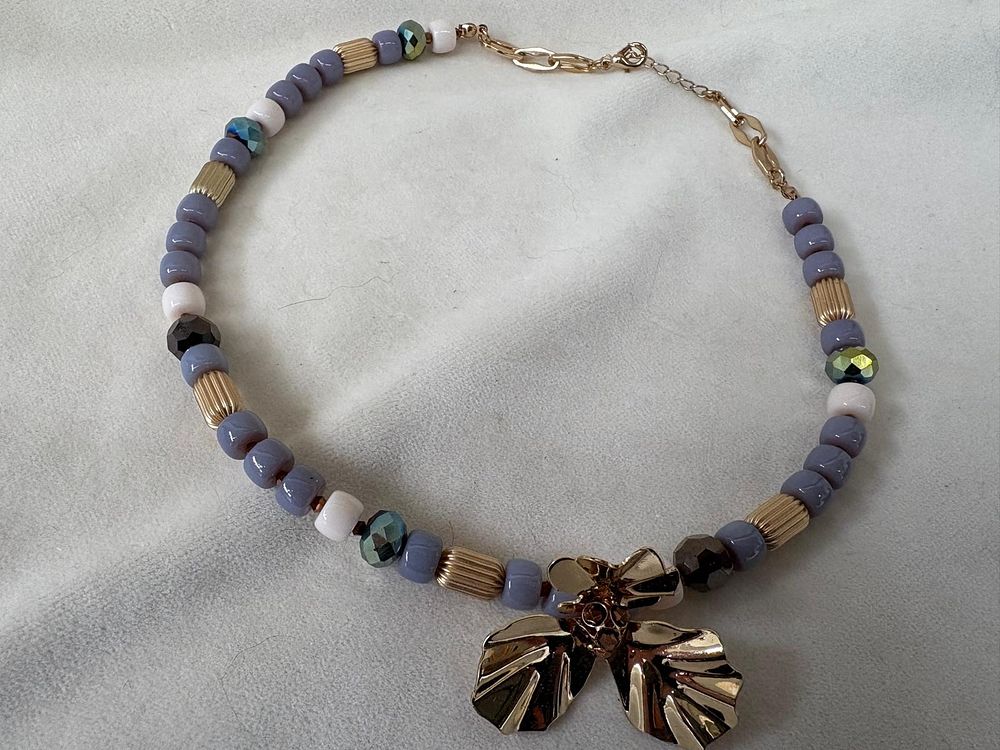 Necklace with gemstones and a gold-tone metal flower appliqu&eacute;. Signs of wear.