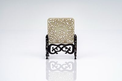 Placca in giada bianca traforata con figure e nuvole stilizzate, su base lignea. Cina, fine 