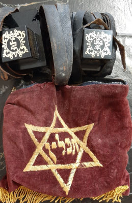 תפילין בנרתיק בד ישן. 
לא נבדק כשרות. 
קרע בנרתיק הבד.