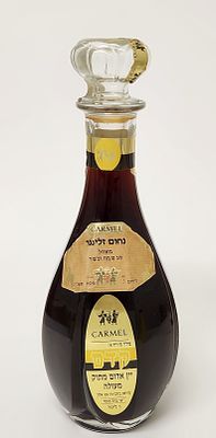 כרמל מזרחי – יין קדם, מילוי א – יין אדום מתוק מעולה. תשנ"ה. 1 ליטר. הפלומבה קרועה אך נראה כי 