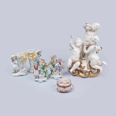 Lote em porcelana: Grupo escultur&oacute;rio "Tr&ecirc;s Cupidos"; Dois pares de jarrinhas e caixinha; 