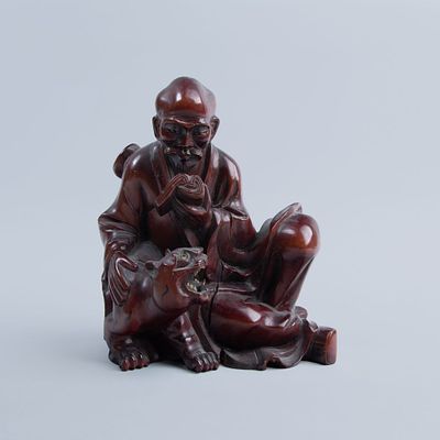 Escultura chinesa em madeira entalhada representando Luohan e tigre. Dim: 18 x 15 cm