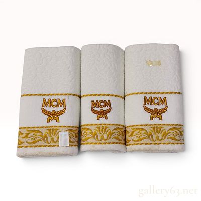 A Trio of MCM Branded Hand Towels. A trio of white cotton hand towels featuring the MCM logo. 