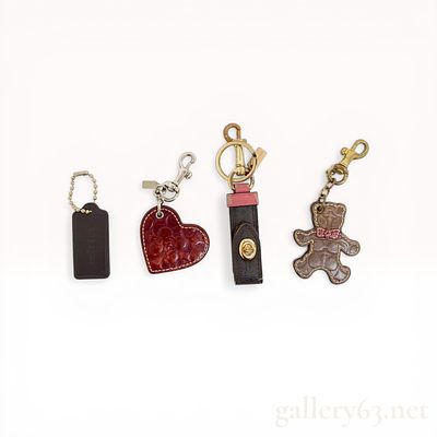 An Assortment of Four Coach Leather and Canvas Bag Charms. Coach collection of four bag charms 