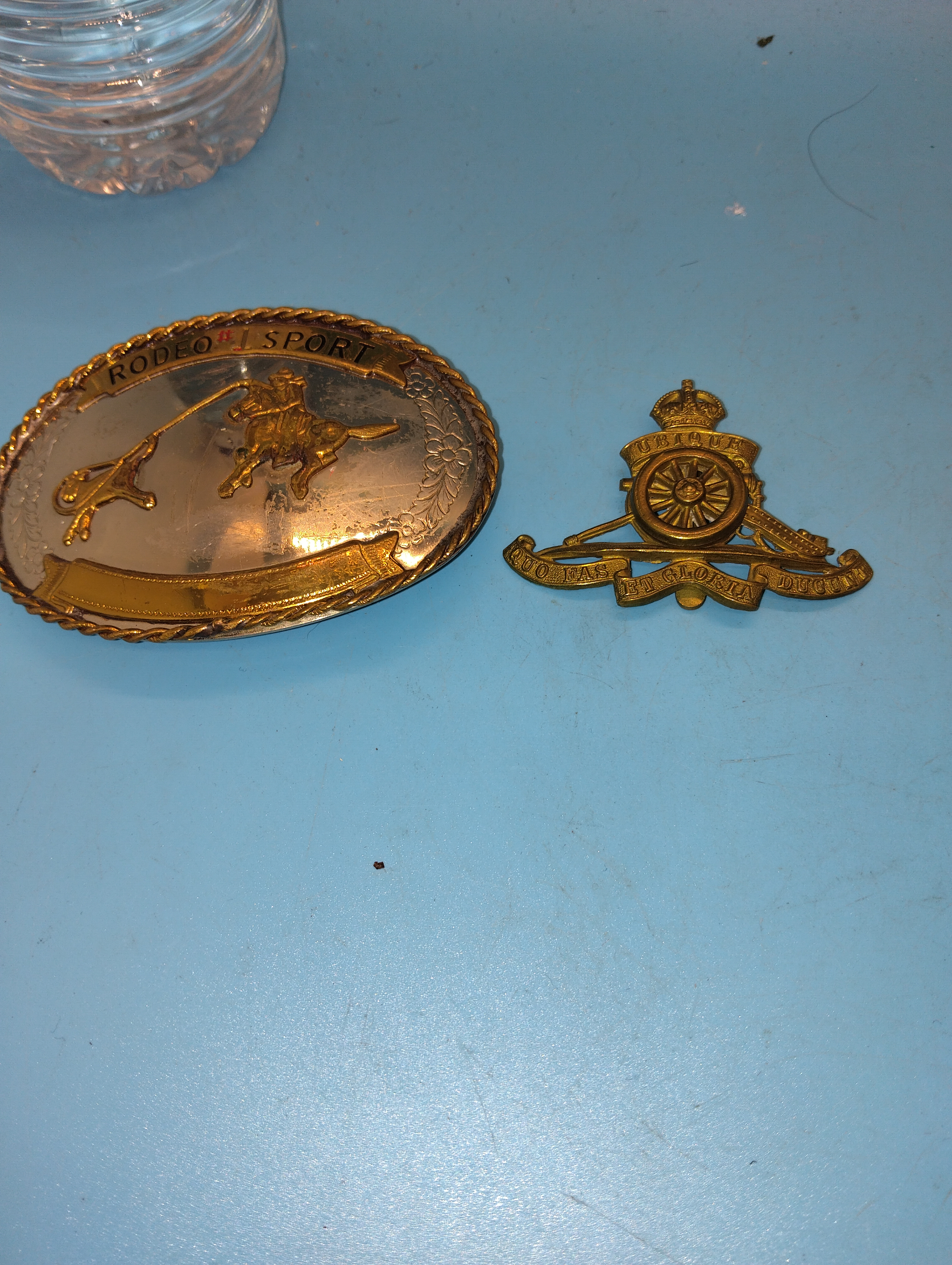 BRITISH ARMY ROYAL ARTILLERY CAP BADGE AND AN RODEO BELT BUCKLE