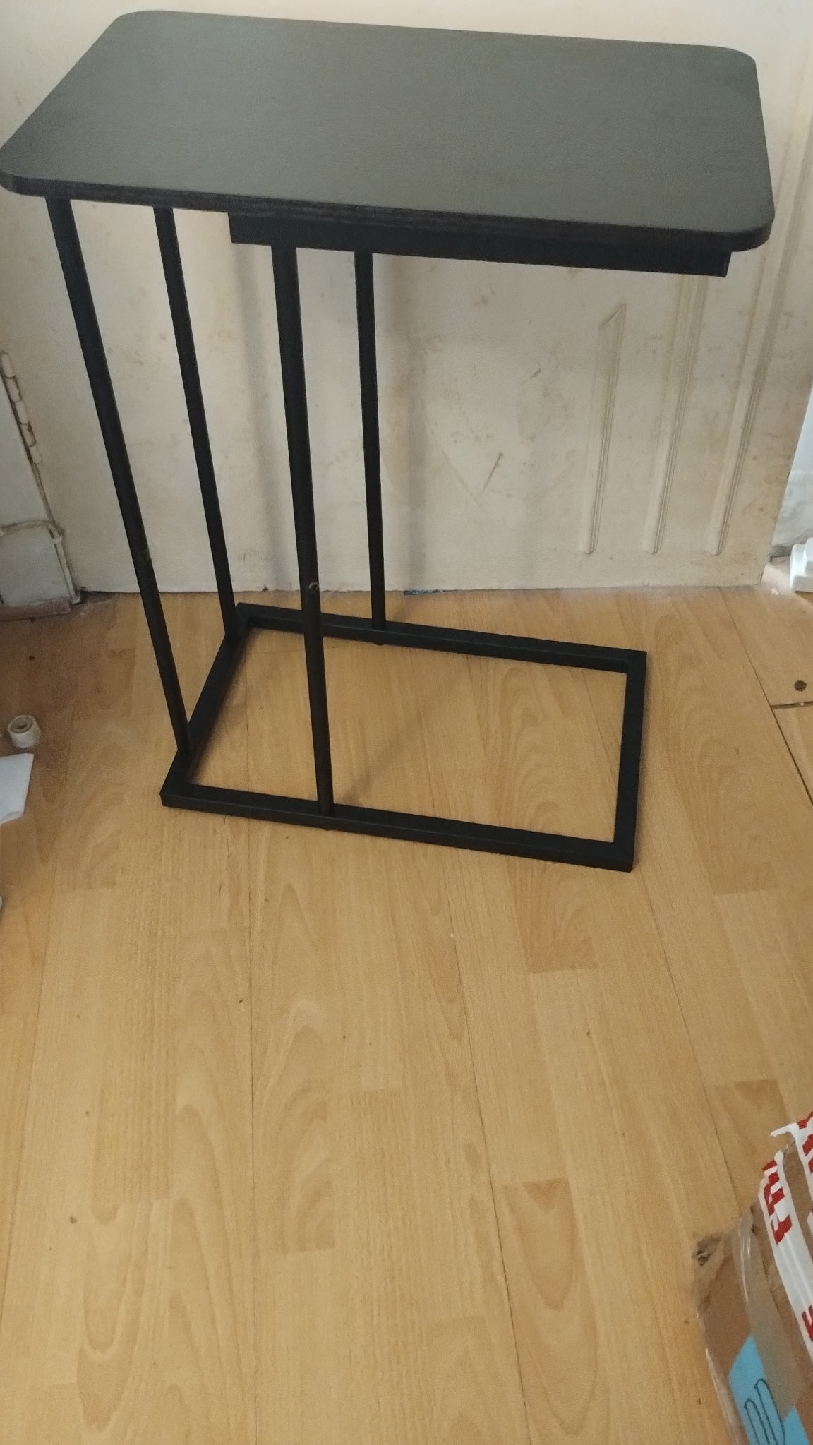 A NEW BOXED contemporary matt black metal and laminate C-shaped side table