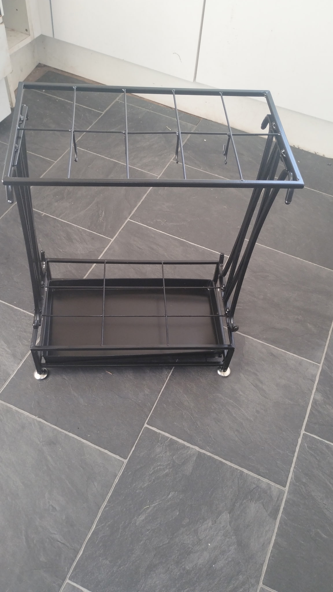 A NEW BOXED contemporary black-finished metal umbrella stand with ten slots and integrated hooks