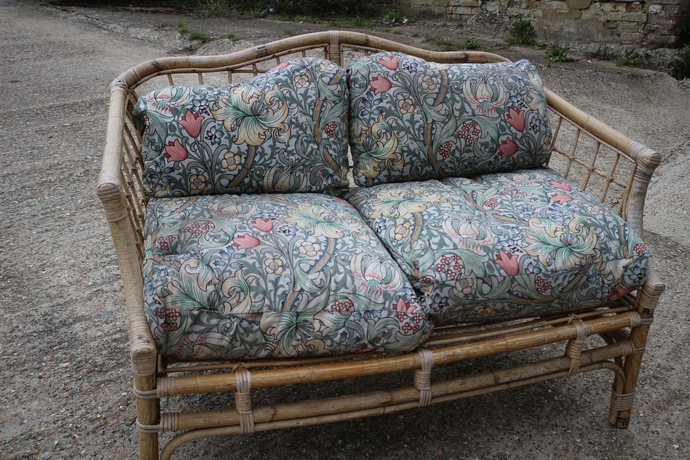 Lot 412: A Two-Seater Rattan Sofa with Floral Cushions