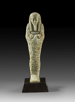 Shabti of light green faience. Shabti of light green faience, H 17cm (without wooden stand). 