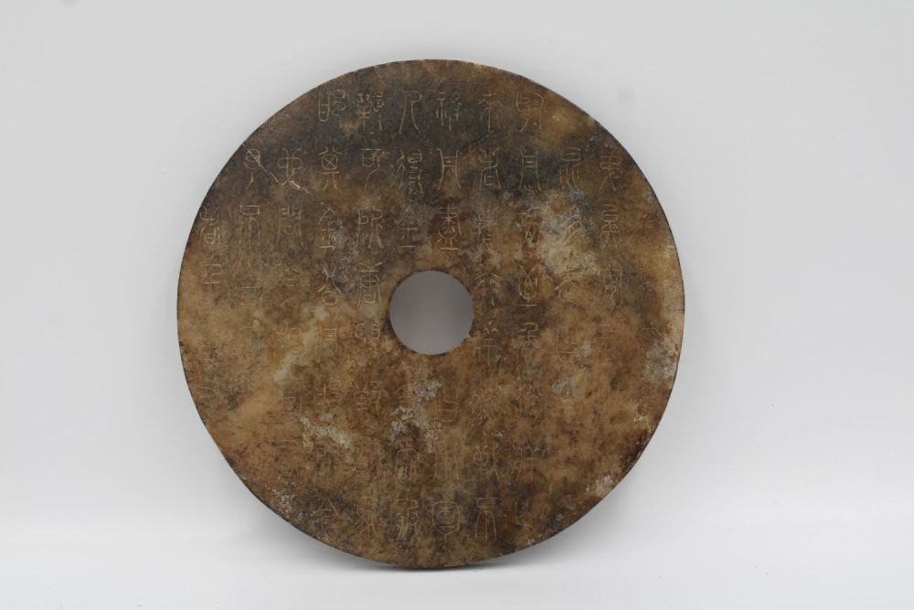 Lot 76: Chinese bi jade disc decorated with symbols.