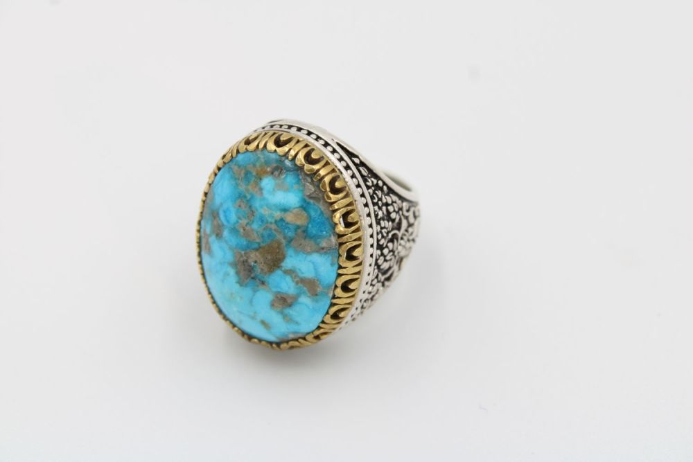 Lot 197: A men's silver ring featuring a striking turquoise...