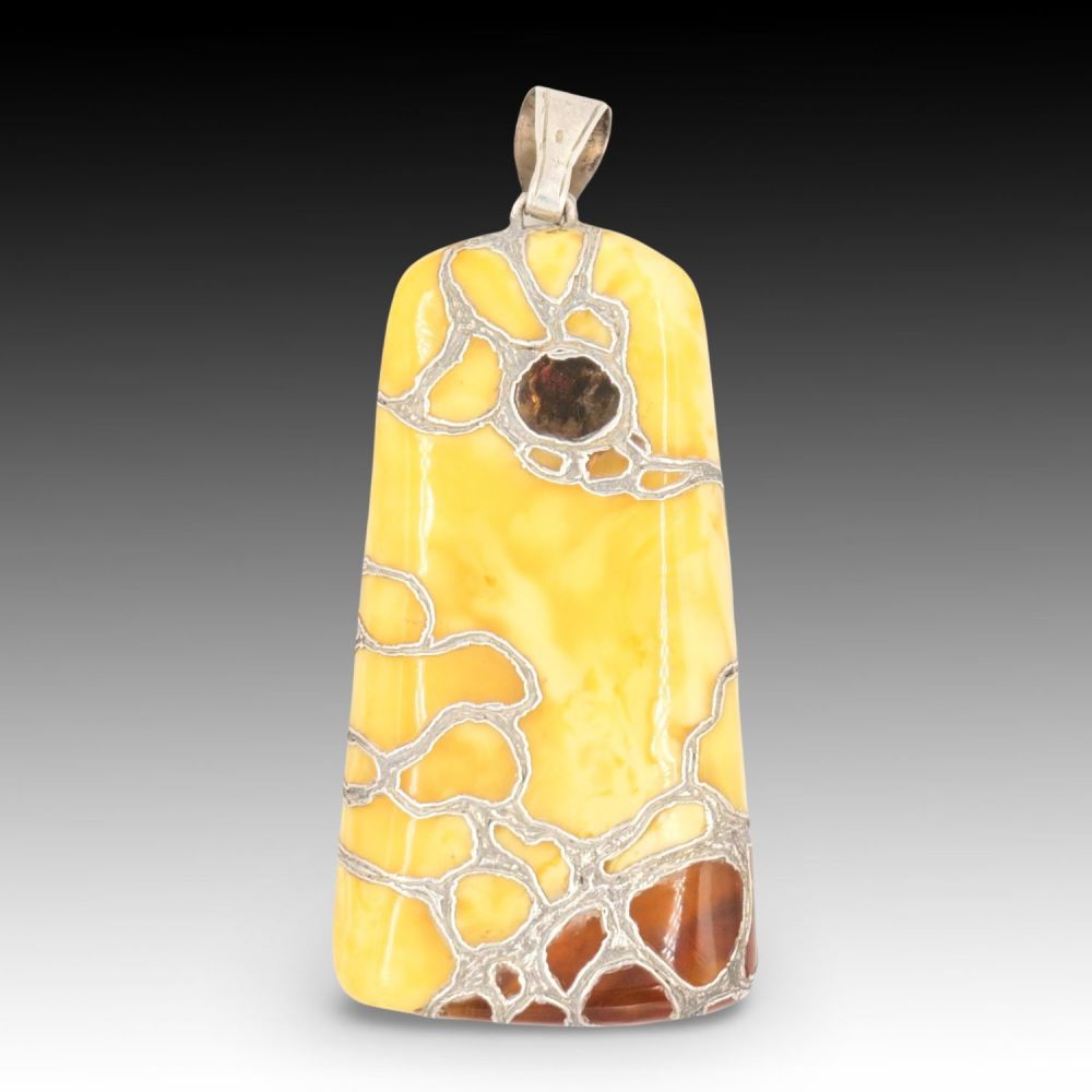Lot 428: A Butterscotch Amber Pendant with Intricate Silver Inlay