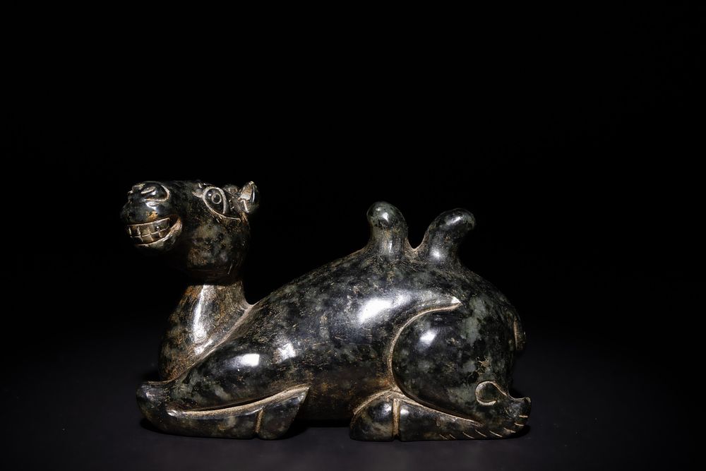Lot 252: A Chinese Carved Green and Russet Jade Camel...