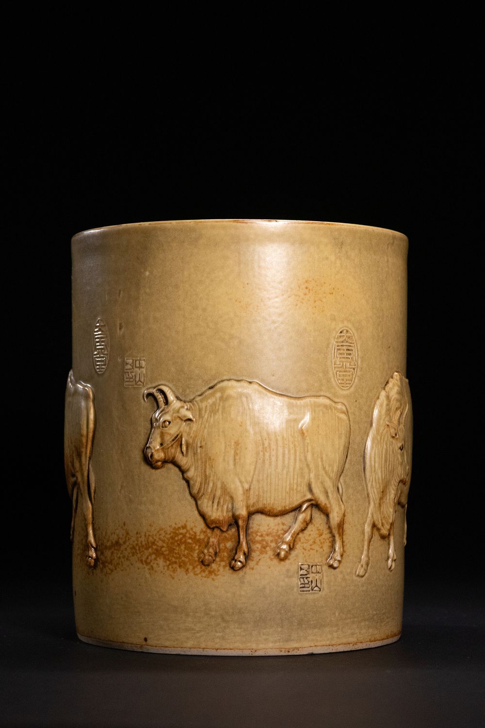 Lot 320: A Chinese Celadon-Glazed Porcelain Brushpot with Relief Oxen.