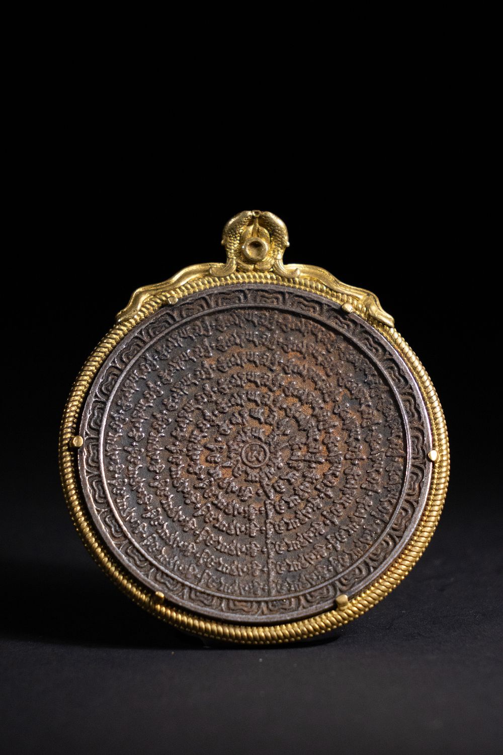 Lot 216: A Tibetan Gilt-Bronze Circular Prayer Amulet with Script...