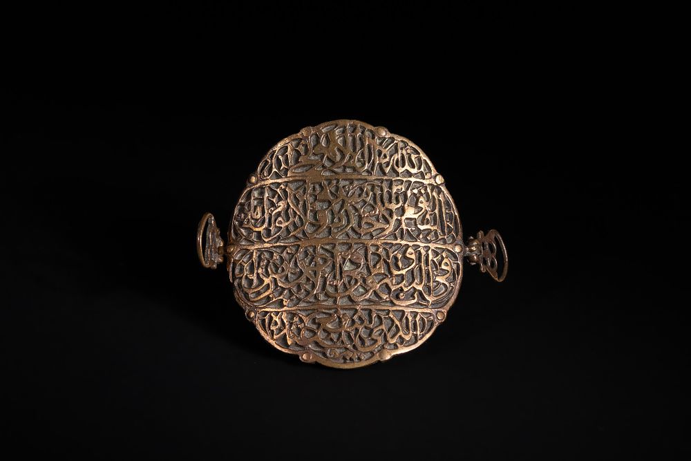 Lot 169: An Islamic Brass Openwork Bazuband with Calligraphic Panels.
