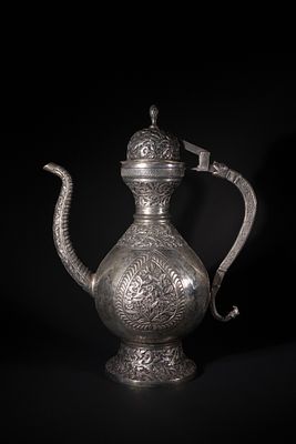 A Indo-Persian White Metal Ewer - This elaborately decorated ewer features a bulbous body, a 