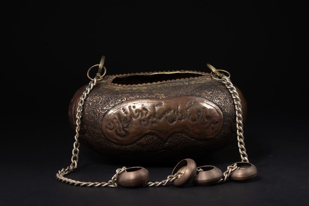 Lot 162: A Persian Engraved Copper Kashkul Beggar’s Bowl with...