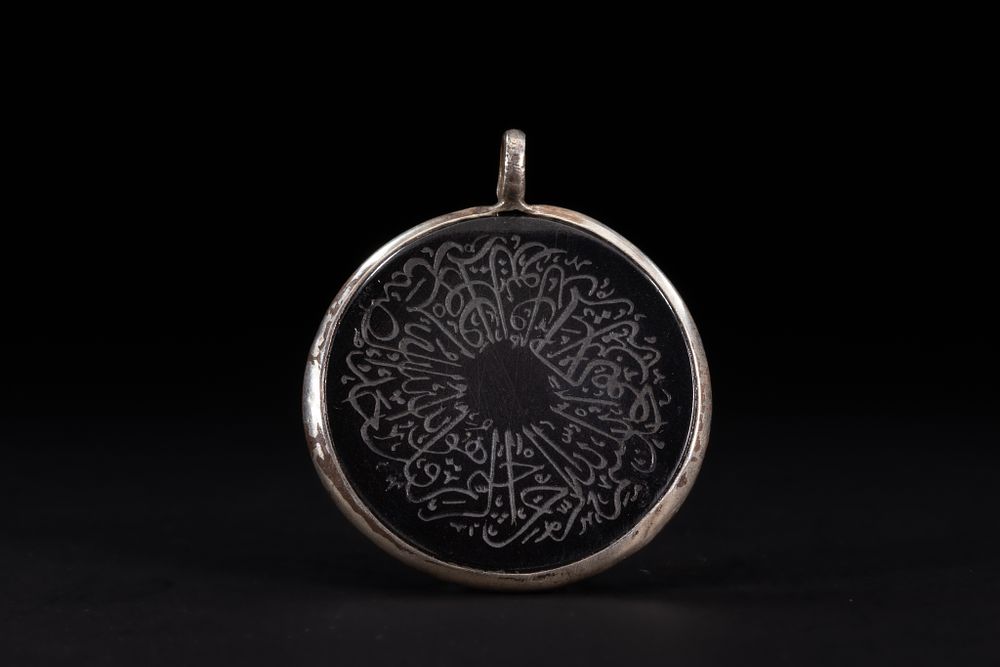 Lot 177: An Islamic Circular Black Hardstone Amulet Pendant with...